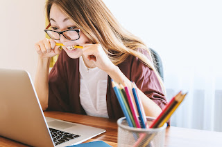 Woman staring at a laptop screen biting a pencil